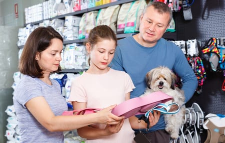 friendly cheerful  glad family with little dog buying pet supplies in store