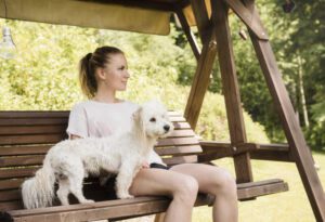 woman sitting on swing with coton de tulear puppy